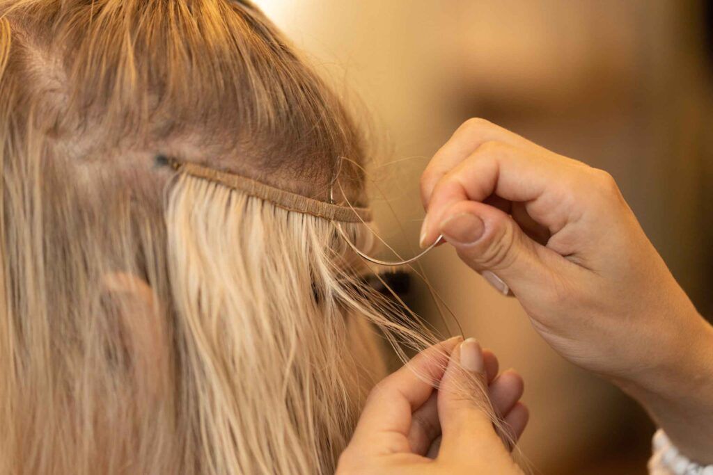 lient receiving a hair extension touch-up at Lima Beauty Salon